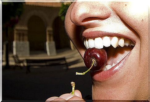 Woman eating a cherry because she doesn't grind her teeth