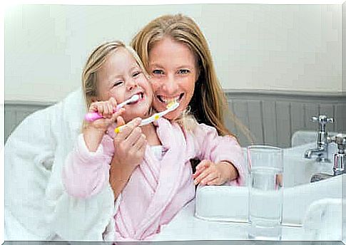 Mother teaching her daughter to brush her teeth.