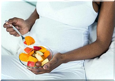 pregnant woman eating fruit salad